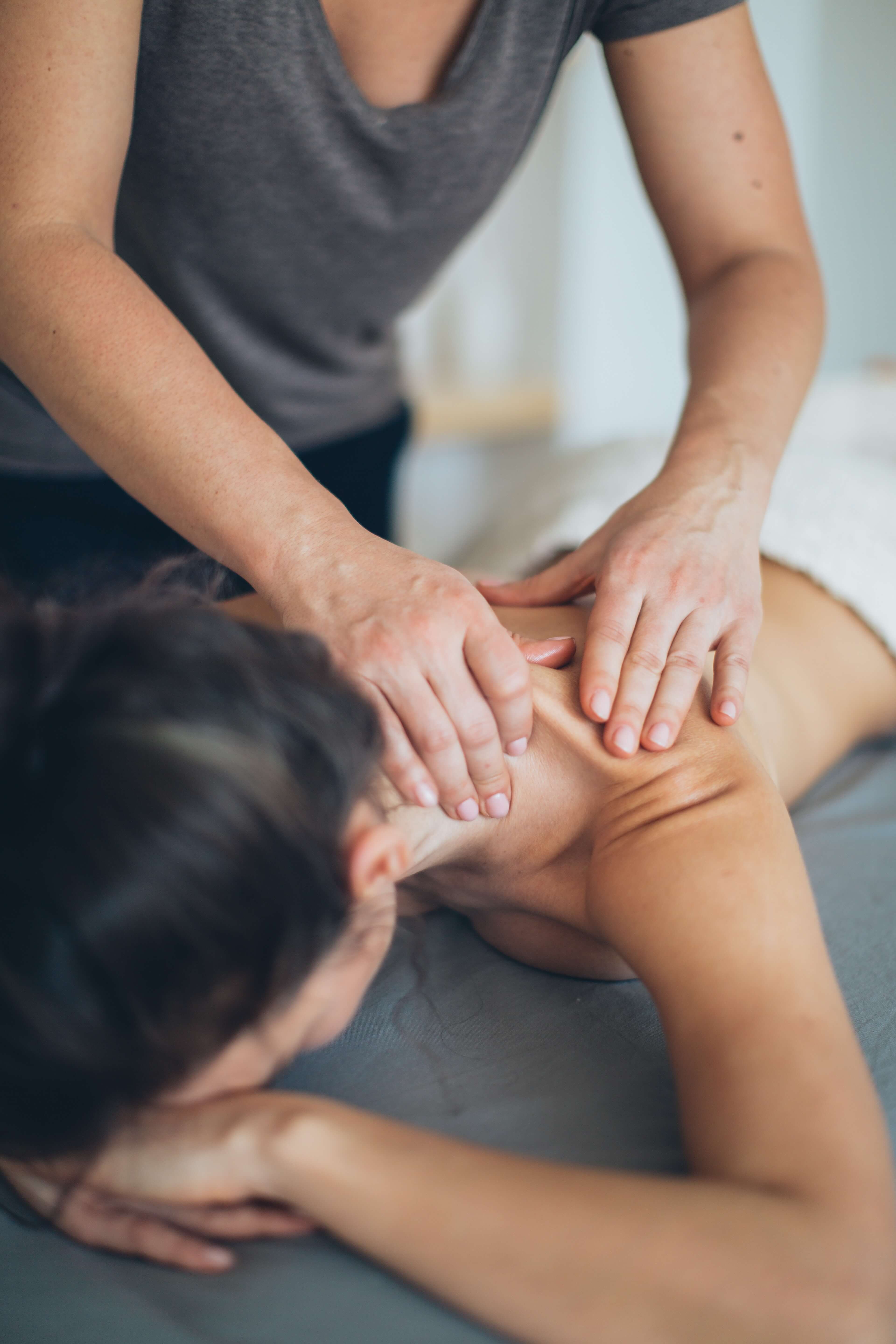 Mulher de bruçus recebendo massagem no ombro